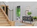Bright foyer with light wood floors, wood staircase, iron railing, and view to living space through doorway at 402 Chattahoochee St, Roswell, GA 30075