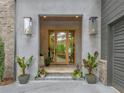 Inviting entryway with modern lighting fixtures, a glass front door, and decorative potted plants at 402 Chattahoochee St, Roswell, GA 30075