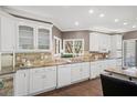 Bright kitchen featuring white cabinetry, granite countertops, tile backsplash, and stainless steel appliances at 649 Lakeshore Dr, Berkeley Lake, GA 30096