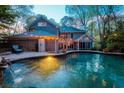 Backyard pool area with brick home, water features, string lights, mature trees, and patio at 649 Lakeshore Dr, Berkeley Lake, GA 30096