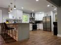 This kitchen features white cabinets, stainless steel appliances, a center island with seating, and wood flooring at 1155 Christian Se Cir, Conyers, GA 30013