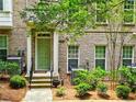Brick townhome boasts a covered entry, lush landscaping, and a welcoming green door and mature trees at 2168 Rock Creek Park, Decatur, GA 30033
