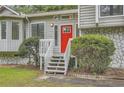 Close-up of a house with a stone foundation and a bright red door with decorative bushes at 1945 Chateau Ln, Lithia Springs, GA 30122