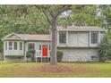 Charming home featuring stone accents, a red front door, a well-maintained lawn and mature trees at 1945 Chateau Ln, Lithia Springs, GA 30122