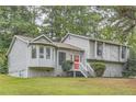 Charming home featuring stone accents, a red front door, a well-maintained lawn and mature trees at 1945 Chateau Ln, Lithia Springs, GA 30122