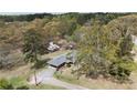 An aerial shot shows the home nestled in a serene landscape with mature trees and a long driveway at 6957 Mason Creek Rd, Douglasville, GA 30135