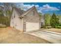 View of home featuring a brick and stone facade, two-car garage, and side yard at 164 Madison Grace Ave, Mcdonough, GA 30252