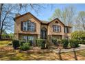 Beautiful brick home with stone accents, manicured bushes, and a stairway to the front door at 5960 Sarah Orr Ln, Cumming, GA 30040
