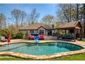 Inviting backyard pool area with a covered lounge, hot tub, and manicured lawn at 5960 Sarah Orr Ln, Cumming, GA 30040