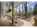 Relaxing covered porch with stone flooring, decorative light fixtures, and scenic views of the tree-lined neighborhood at 250 Martin Ridge Ct, Roswell, GA 30076