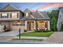 Beautiful home at dusk with manicured lawn, stone and siding details, and a welcoming front porch at 2940 W Village Dr # 60, Suwanee, GA 30024