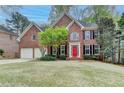 Two-story brick home featuring a red front door, black shutters, and lush landscaping surrounding the well-maintained lawn at 10460 Cranchester Way, Alpharetta, GA 30022