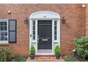 Close up of a brick townhouse, featuring a black front door with white trim, stylish outdoor lighting, and small topiary trees at 4620 Wieuca Ne Rd # 24, Atlanta, GA 30342