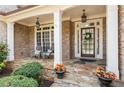 Inviting front porch with stone floor, rocking chairs, and flower pots by the entrance at 1060 Meadow Brook Dr, Woodstock, GA 30188