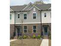 Well-maintained townhome featuring a brick facade, gray siding, and tidy front lawn at 1282 Ainsworth Aly, Sugar Hill, GA 30518