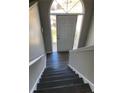 Dark wood staircase leading to a bright entryway featuring a door with transom window at 2250 Camp Town Way, Lawrenceville, GA 30044
