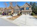 Lovely townhome with a two-car garage, long concrete driveway, and mature landscaping at 6160 Shiloh Woods Dr, Cumming, GA 30040
