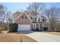 A two-story brick home with an attached garage and long driveway, surrounded by mature trees at 1110 Croftmoore Lndg, Suwanee, GA 30024