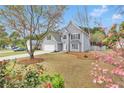 Inviting two-story home with gray siding, manicured lawn, and blossoming trees in the front yard at 2061 Emerald Dr, Loganville, GA 30052