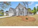 Charming two-story home with gray siding, attached garage, and tree in the front yard at 2061 Emerald Dr, Loganville, GA 30052