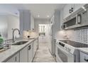 White kitchen with marble counters, gray flooring, black hardware and stainless steel appliances at 300 Johnson Ferry Ne Rd # A1008, Atlanta, GA 30328