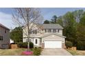 Traditional two-story home with a manicured lawn, blooming tree, and two-car garage at 1924 Sweet Flag Rd, Lawrenceville, GA 30045