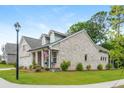 Beautiful exterior brick home featuring dormers, a landscaped yard, and sidewalk access at 437 Great Pine Way, Woodstock, GA 30188