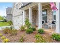 Inviting front porch with elegant columns, stone floor, and professionally landscaped yard at 437 Great Pine Way, Woodstock, GA 30188