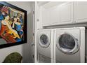 A clean laundry room featuring front-load washer and dryer with white cabinets above and decorative wall art at 3300 Windy Ridge Se Pkwy # 612, Atlanta, GA 30339