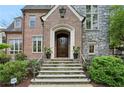 Elegant stone steps leading to a dark wood front door with brick and stone accents and manicured bushes at 603 E Paces Ferry Ne Rd, Atlanta, GA 30305