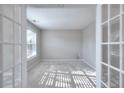 Bright office space with French doors, carpet flooring, and a large window offering serene outdoor views at 3320 Gardenside Dr, Loganville, GA 30052