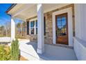 Inviting front porch featuring stone accents, white columns, and a wood front door at 3330 Hillshire Dr, Cumming, GA 30028
