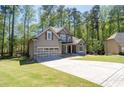 Attractive two-story home featuring gray siding, stone accents, a two-car garage, and a wide driveway in a serene wooded neighborhood at 2050 Heritage Green Dr, Marietta, GA 30064