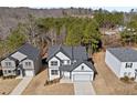 Aerial view of new construction home with two-car garage surrounded by lush greenery and trees at 3205 Tackett Rd, Douglasville, GA 30135