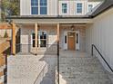 Inviting front porch with brick details, wooden columns, and stylish hanging lights at 52 Lake Overlook Dr, White, GA 30184