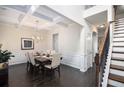 This dining room features dark wood floors, decorative wainscoting, a coffered ceiling and stairs to the second floor at 6540 Muirfield Pt, Fairburn, GA 30213