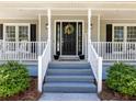Charming front porch with gray steps and a black front door adorned with a wreath at 3227 Heritage Way, Buford, GA 30519