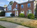 Inviting two-story brick home featuring a manicured lawn and an attached two-car garage at 2875 Oak Meadow Dr, Snellville, GA 30078