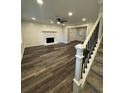 Bright living room features a stone fireplace, modern ceiling fan, and beautiful flooring adjacent to carpeted stairs at 695 Pine Shadows Dr, Dallas, GA 30157