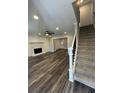 Bright living room features a stone fireplace, modern ceiling fan, and beautiful flooring adjacent to carpeted stairs at 695 Pine Shadows Dr, Dallas, GA 30157