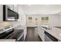 Modern kitchen features stainless steel appliances, granite countertops, white cabinets, and a hardwood floor at 12093 Conrad Circle, Hampton, GA 30228