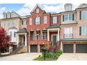 Charming townhome boasts brick facade, a two-car garage, and inviting entry with wrought iron details and manicured landscaping at 1423 Montclair Se Ct # 12, Smyrna, GA 30080