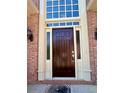 Elegant front door with sidelights and transom window, framed by brick and cream-colored trim at 560 Hunt River Way, Suwanee, GA 30024