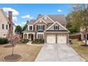 Inviting home with lush landscaping, stone accents, a two-car garage, and a charming red front door at 552 Lawton Bridge Sw Rd, Smyrna, GA 30082