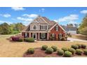 Two story home boasts a beautiful brick facade, manicured landscaping, and a covered front porch with seating at 179 Country Club Dr, Hiram, GA 30141