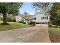 Classic split-level home featuring a two-car garage, manicured lawn, and a cozy, covered front entry at 1068 Gwens Sw Trl, Lilburn, GA 30047