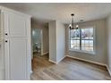 Bright dining area with modern chandelier, wood-look floors, and a view of the neighborhood through a large window at 4480 Maple Valley Dr, Cumming, GA 30040