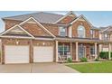 Lovely brick home featuring a spacious two-car garage, covered porch, and well-maintained front lawn at 5085 Mundy Dr, Cumming, GA 30028