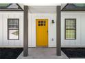 Close-up of a bright yellow front door flanked by windows, and dark support pillars at 1071 N Price Rd, Sugar Hill, GA 30518