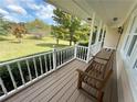 Cozy covered porch with a wooden bench overlooking the spacious, tree-filled front yard at 5791 Warren Farm Sw Rd, Powder Springs, GA 30127